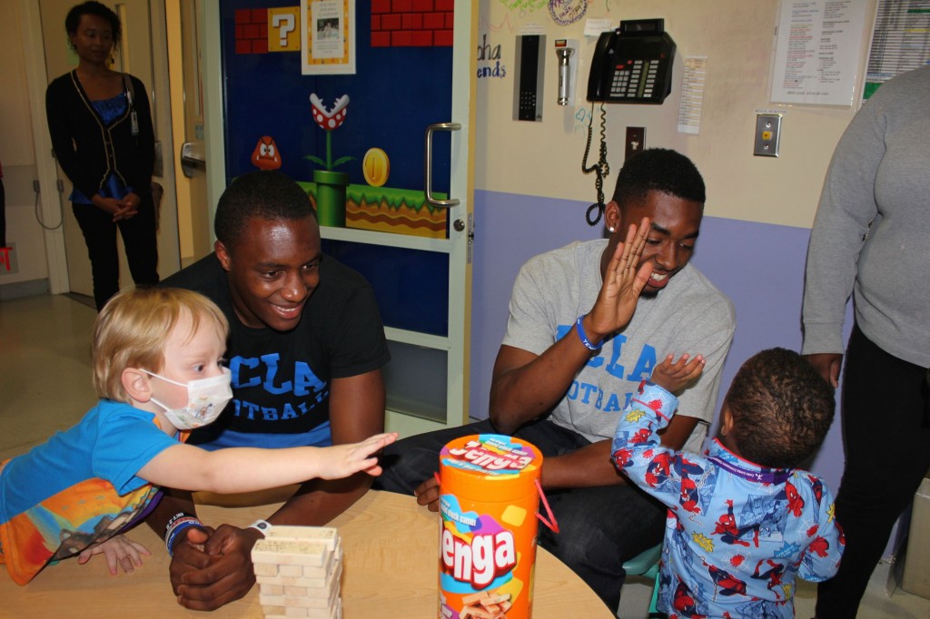 UCLA Bruins football players Aaron Sharp (left) and Jordan Lasley (right) play with patients Kaiden Cressy, 2, (left) and Jhordan Moncrief, 2 on Thursday, July 31.